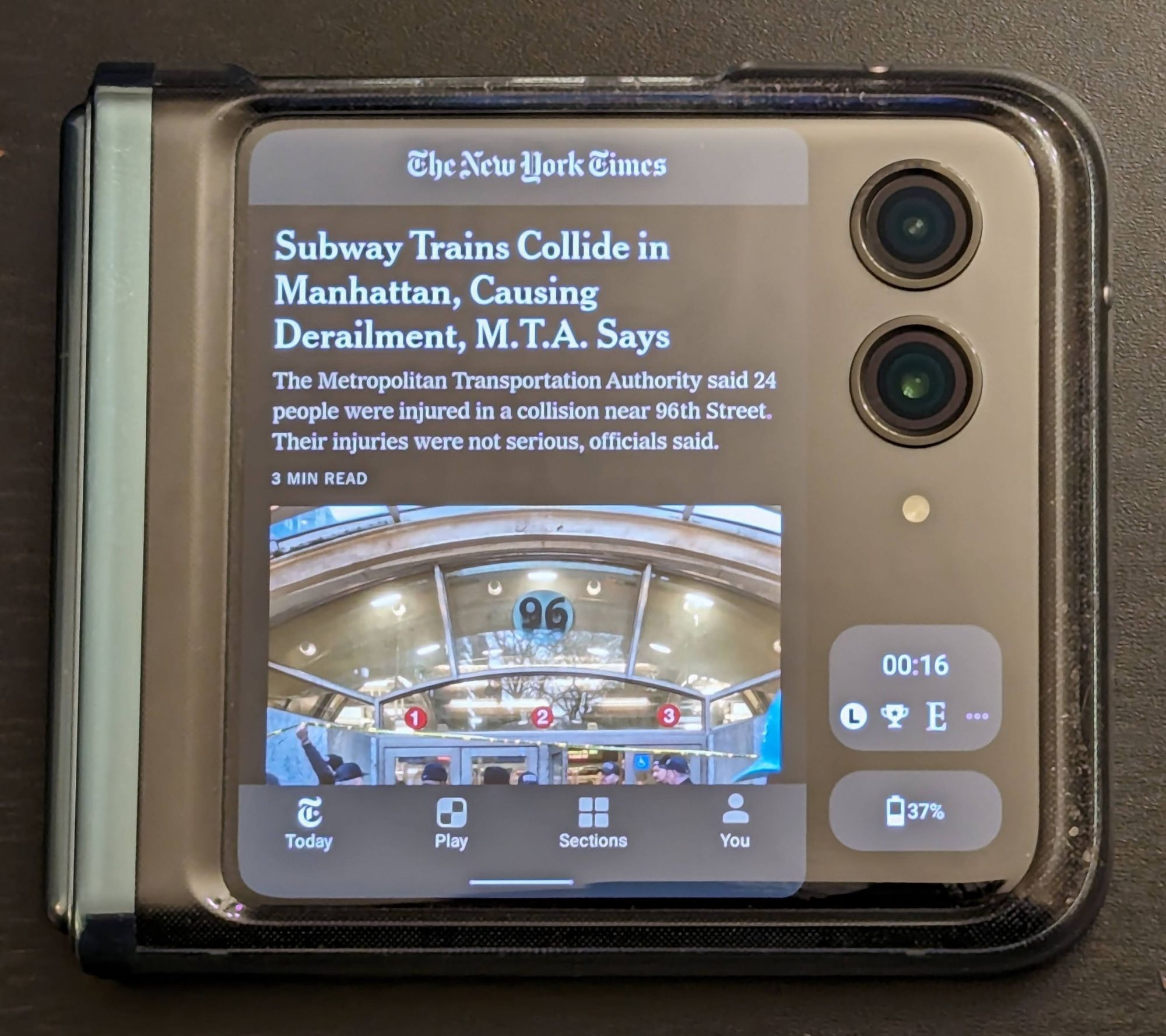 The Razr Plus in a "landscape" orientation while folded, showing the New York Times app taking up the full height of the screen but only covering the width of the screen up to the cameras. Two small widgets appear underneath the cameras (basically the cameras and those widgets essentially appear as a second column besides the open app)